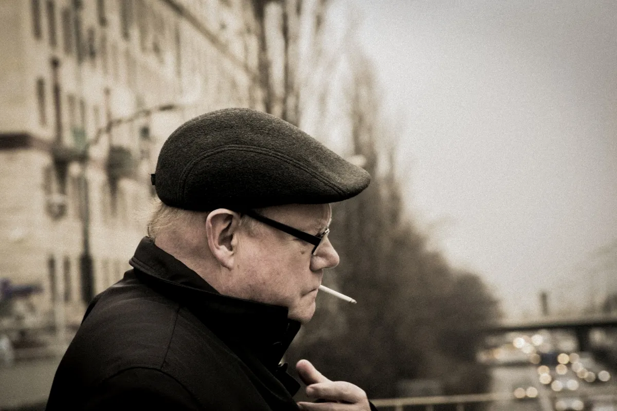 Older man in a flat cap smoking in side profile
